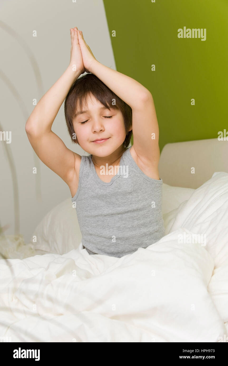 Junge macht Joga im Bett - boy does yoga in bed, Model released Stock Photo