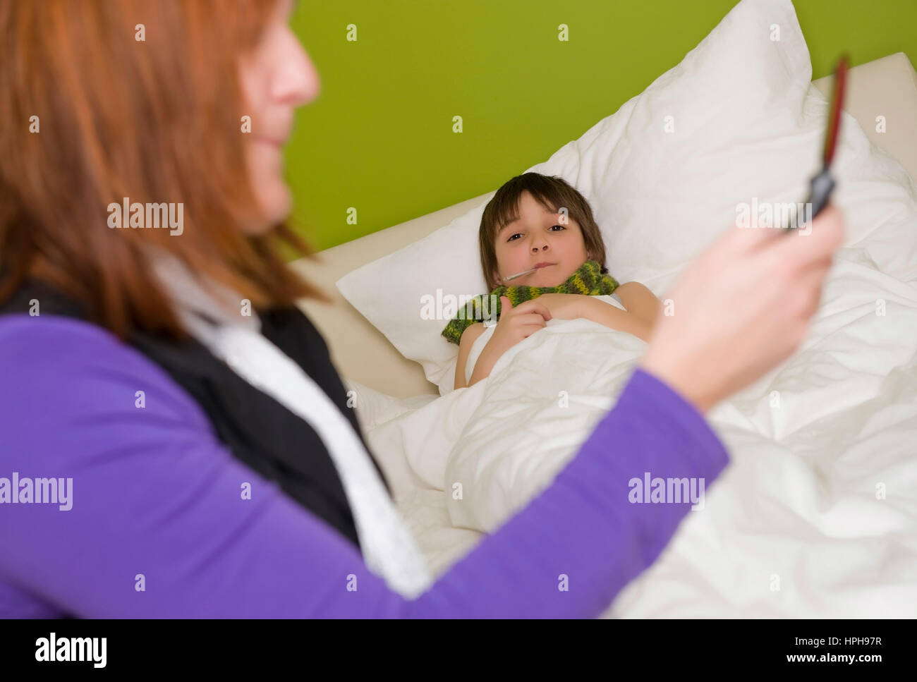 Krankes Kind liegt im Bett, Mutter ruft den Arzt an - child in bed, mother calls the doctor, Model released Stock Photo