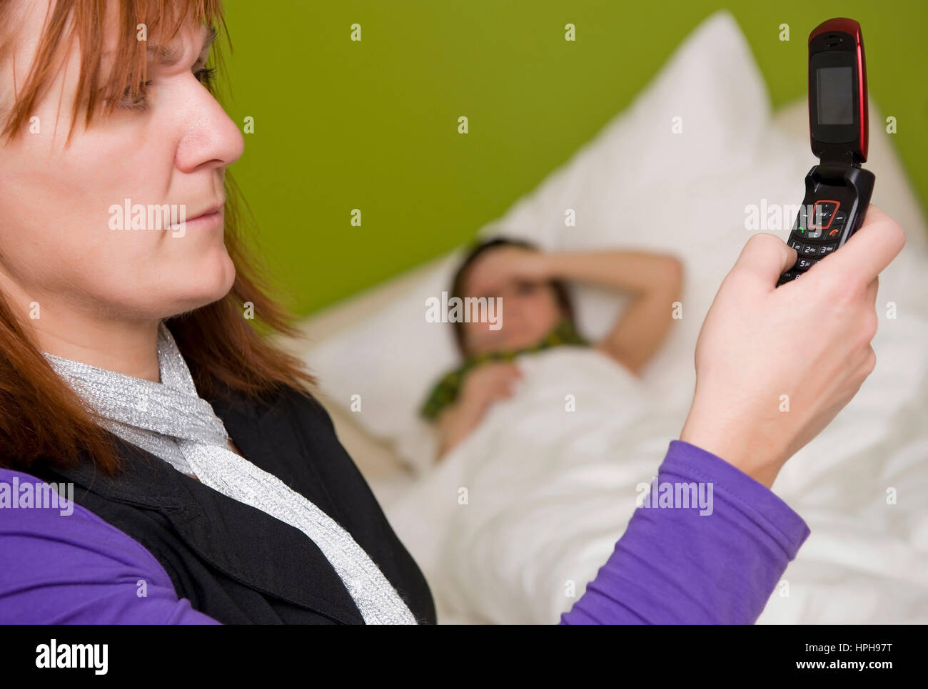 Krankes Kind liegt im Bett, Mutter ruft den Arzt an - child in bed, mother calls the doctor, Model released Stock Photo