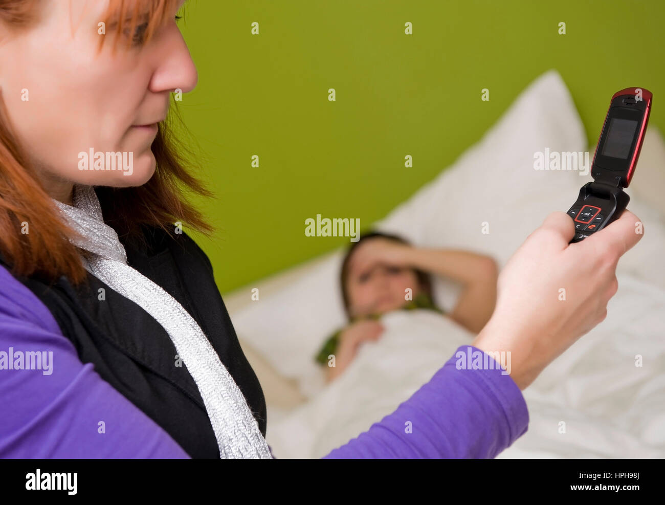 Krankes Kind liegt im Bett, Mutter ruft den Arzt an - child in bed, mother calls the doctor, Model released Stock Photo