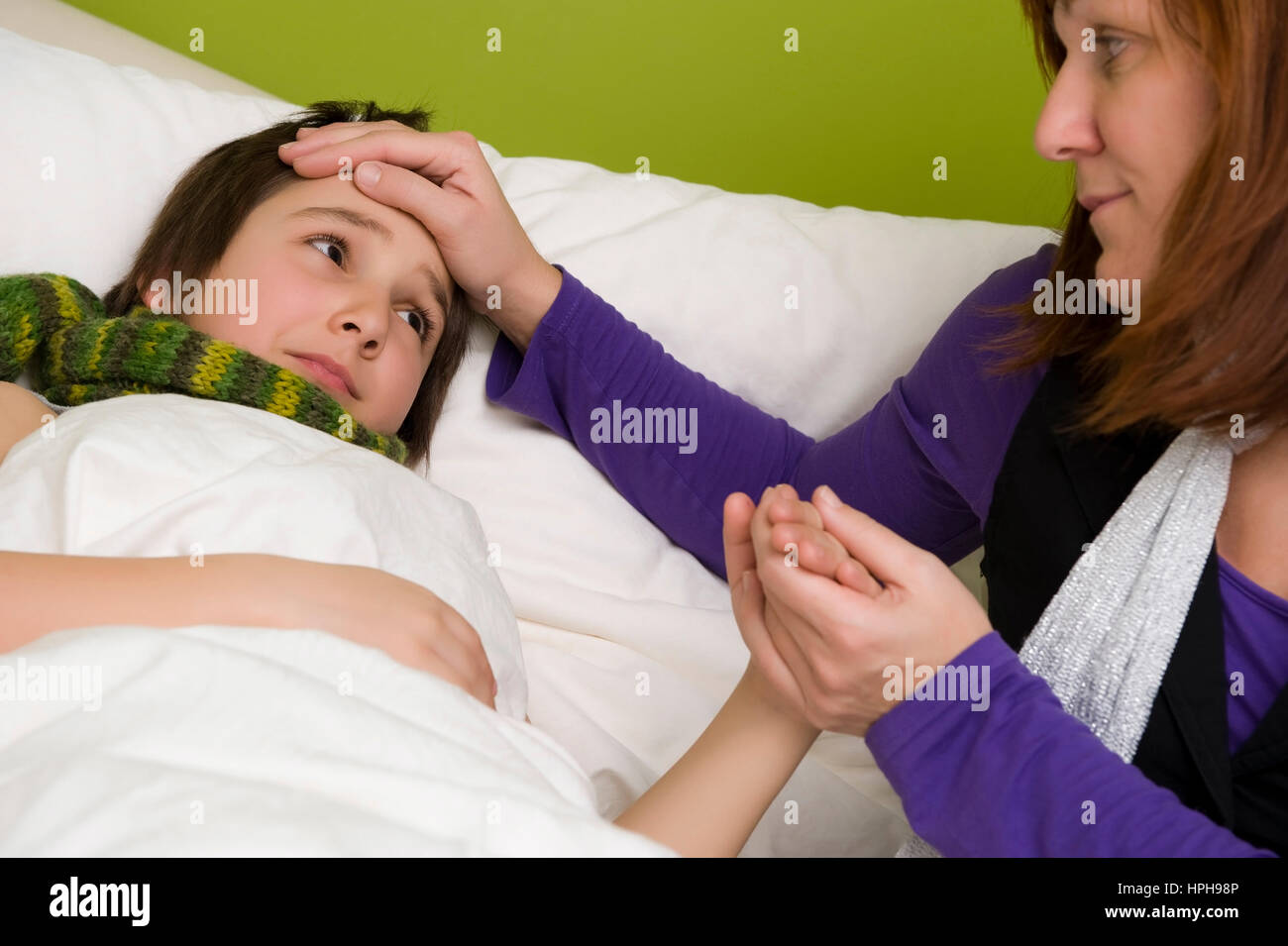 Mutter sitzt am Bett von krankem Sohn - sick son in bed, Model released Stock Photo