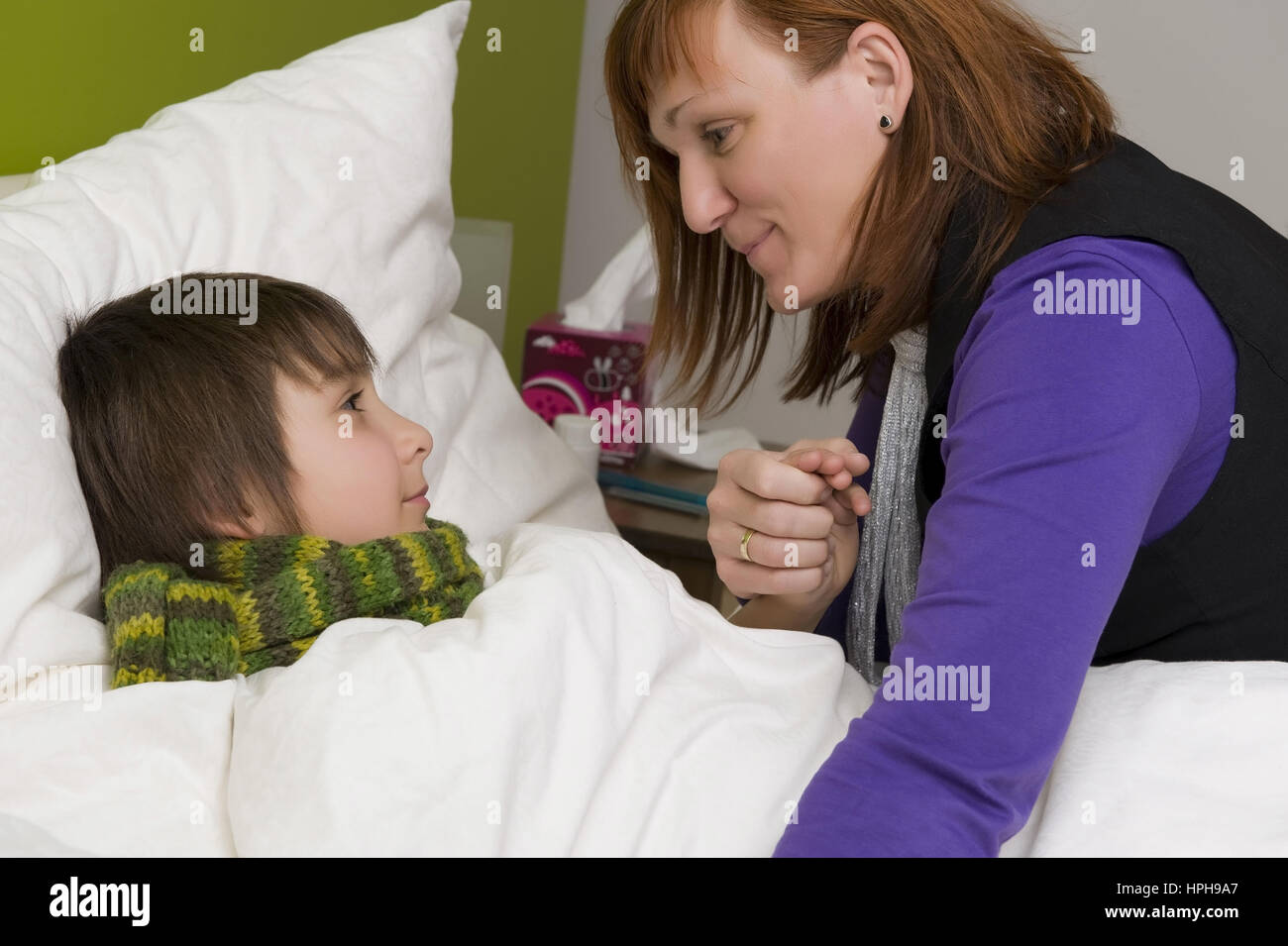 Mutter sitzt am Bett von krankem Sohn - sick son in bed, Model released Stock Photo