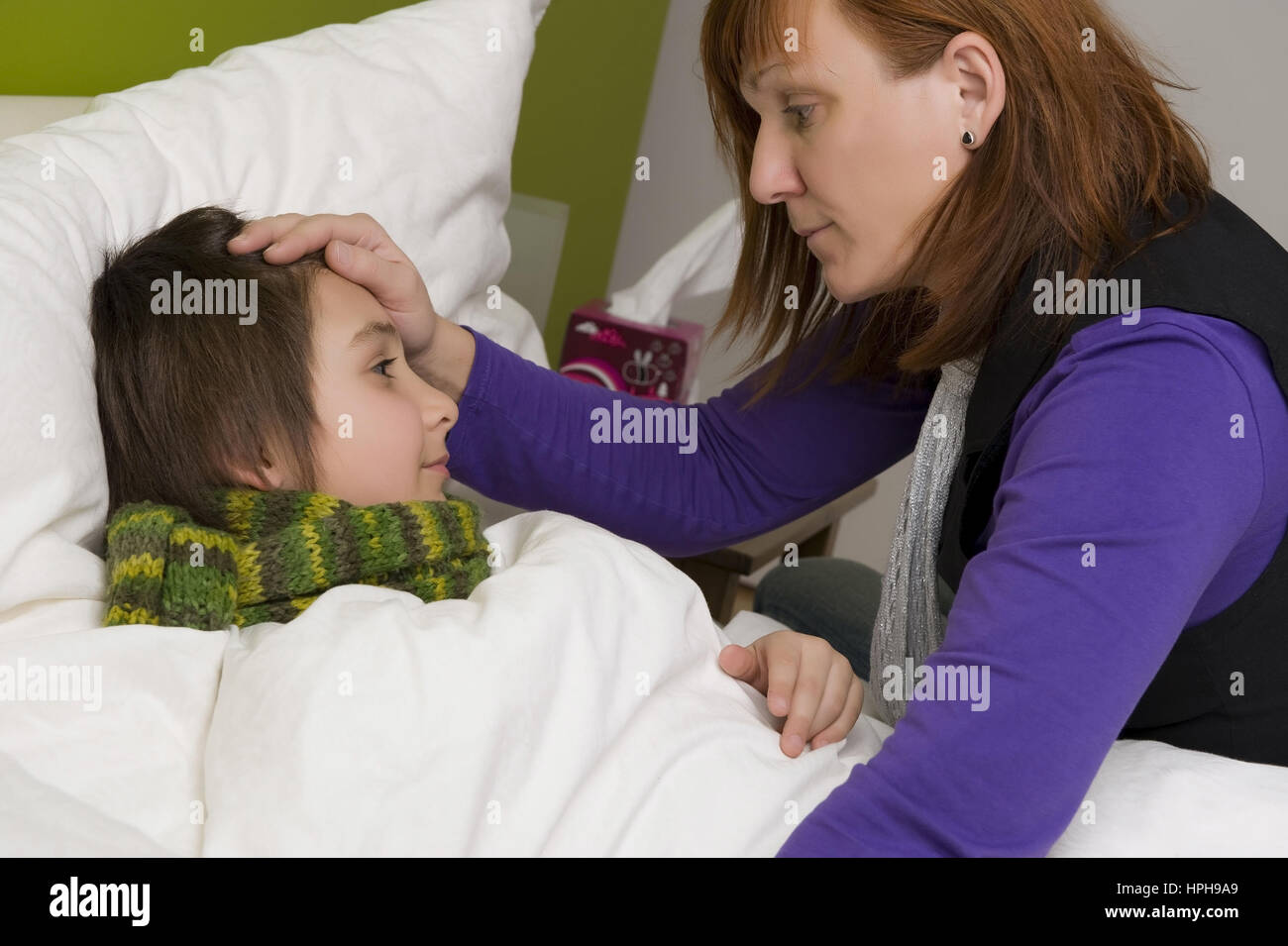 Mutter sitzt am Bett von krankem Sohn - sick son in bed, Model released Stock Photo