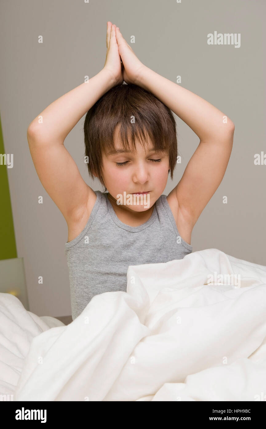 Junge macht Joga im Bett - boy does yoga in bed, Model released Stock Photo