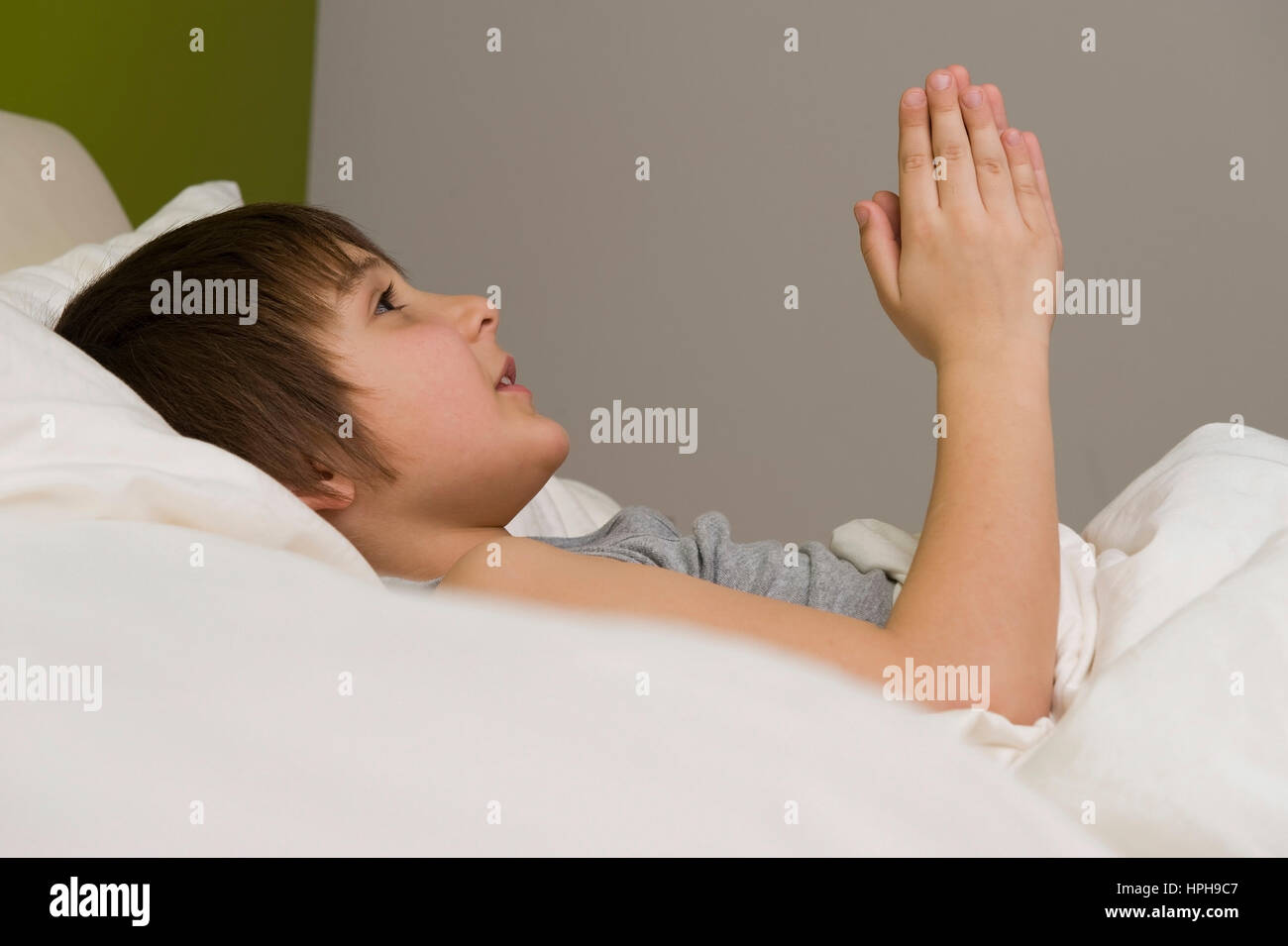 Junge betet vor dem Einschlafen im Bett - boy is praying in bed, Model released Stock Photo