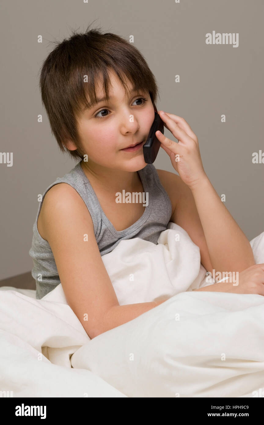 Junge mit Handy im Bett - boy with mobile in bed, Model released Stock Photo