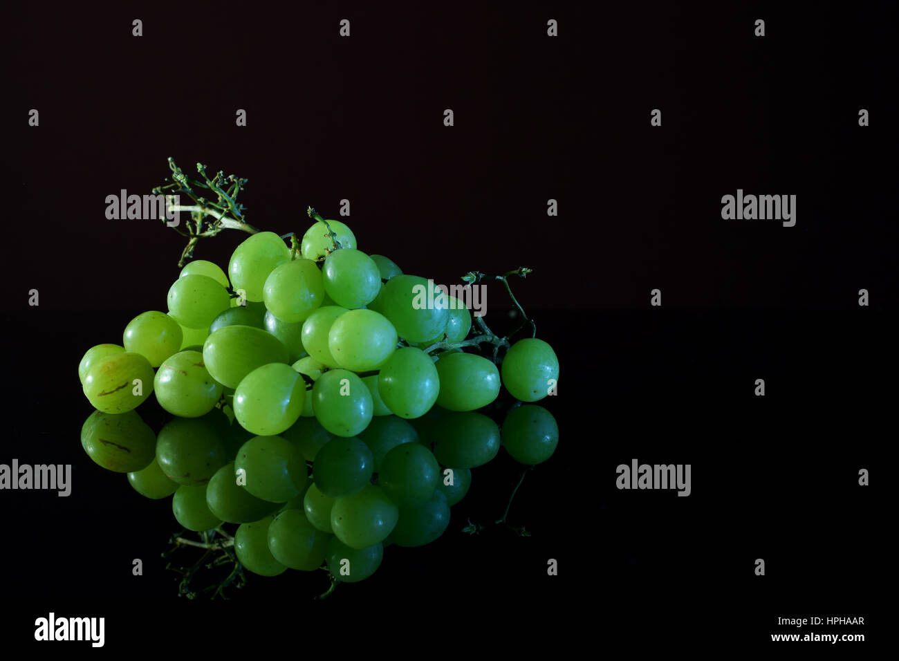 Green grapes on reflective black surface Stock Photo