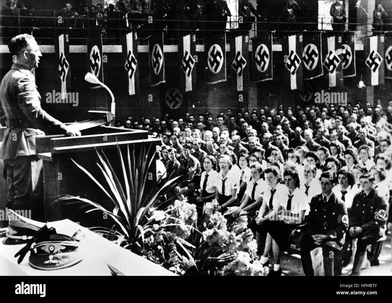 The Nazi propaganda image shows the Chief of Civil Affairs in Luxembourg, Gustav Simon, during his speech to mark the occasion of several specially-selected members of the Luxembourgian Volksdeutsche Bewegung (German People's Movement) being awarded German citizenship in Luxembourg (city). Taken in September 1942. The Nazi propaganda on the reverse of the picture reads, "Luxembourgians become Germans of the Reich. During a major German People's Movement rally, Gustav Simons, Chief of Civil Affairs in Luxembourg, awarded honoured ethnic Germans with German Reich citizenship in front of around 9 Stock Photo