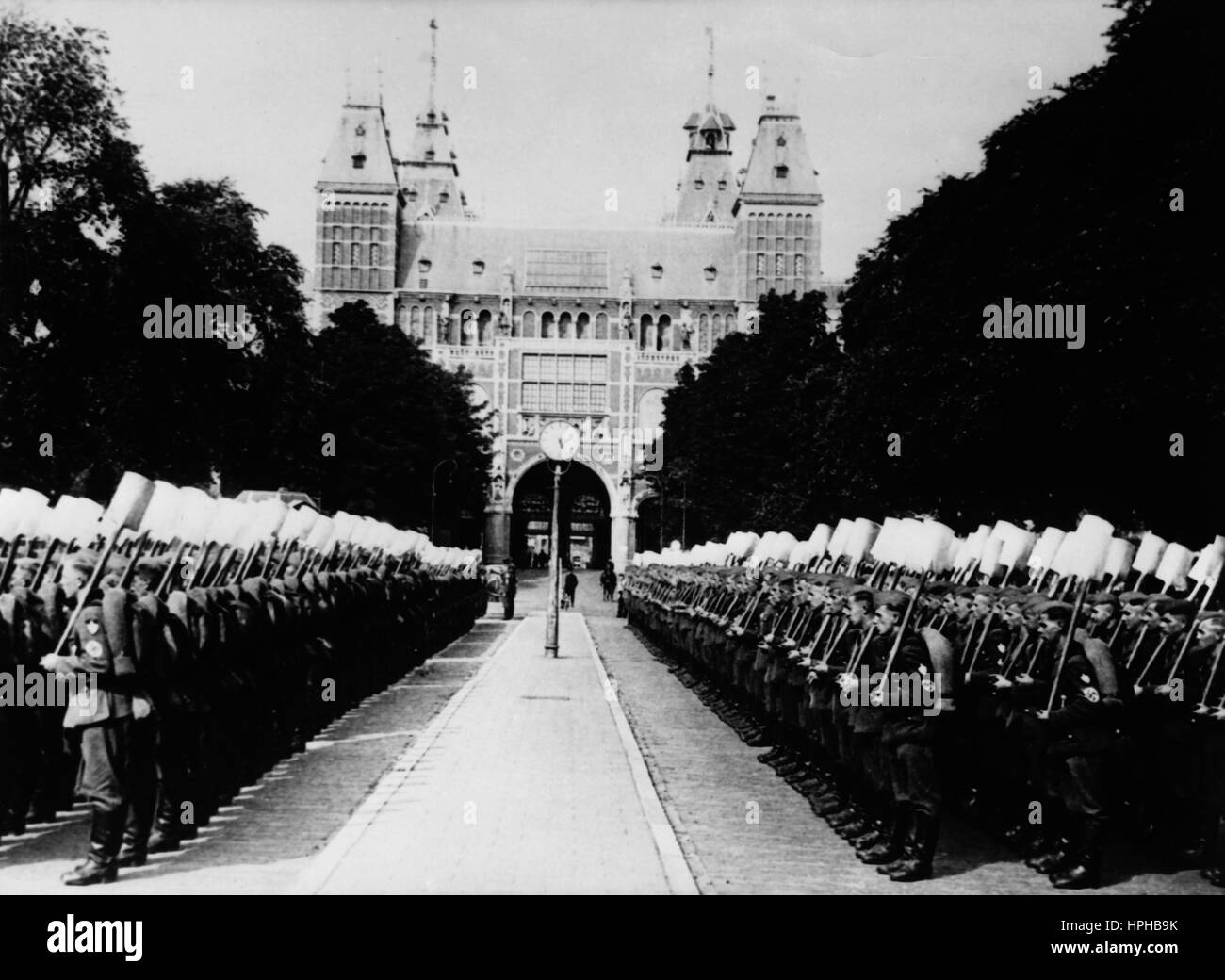 The Nazi propaganda image shows a 'Reichsarbeitsdienst' (Reich Labour Service) march in the occupied Netherlands. Taken in August 1940. In the background is the Rijksmuseum Amsterdam. A Nazi reporter has written on the reverse of the picture on 08.08.1940, 'Reich Labour Service parade in Amsterdam. Amsterdam experienced its first parade with sections of the Reich Labour Service. The march concluded with the passing through of Reichskommissar (Reich Commissioner) Dr Seyss-Inquart. - Reich Labour Service in formation outside the Rijksmuseum (in the background). Fotoarchiv für Zeitgeschichte - Stock Photo