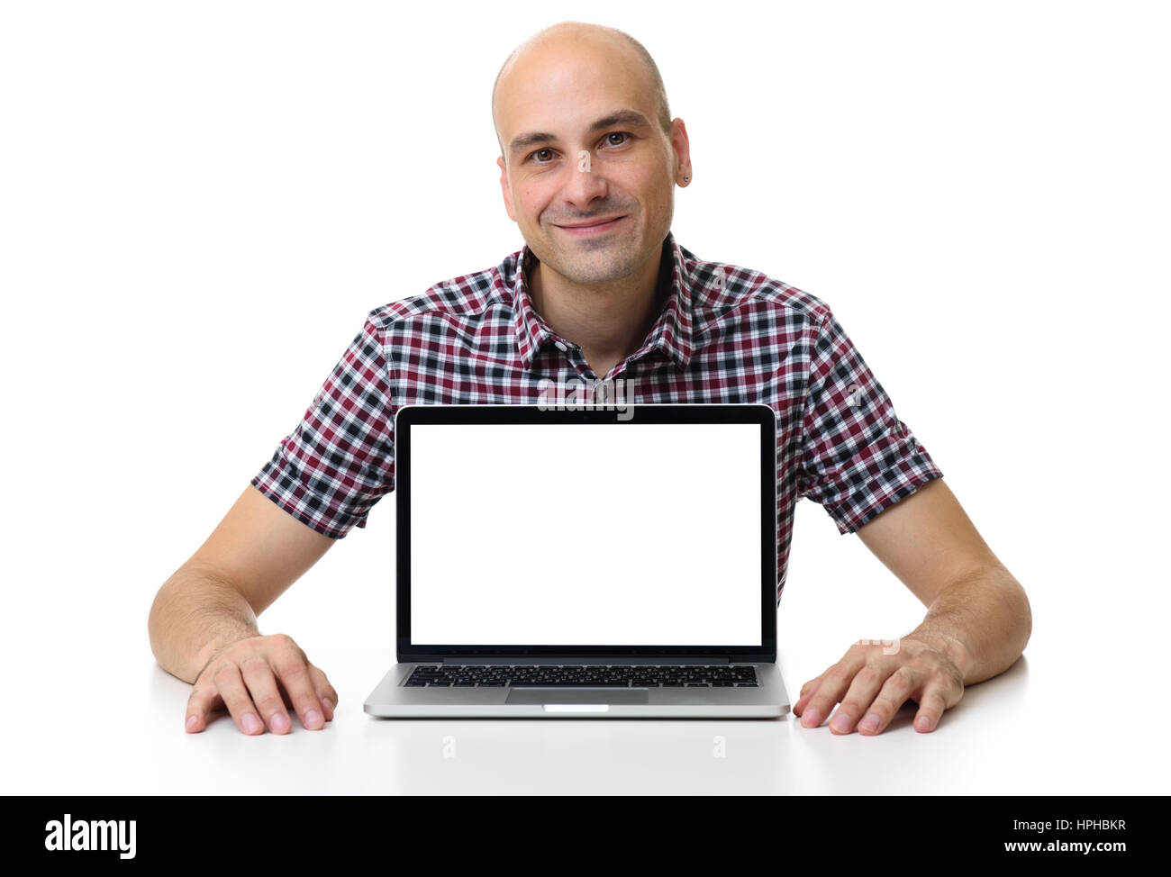 mid age bald man sitting at desk and using laptop. Blank screen with copy space. Isolated on white background Stock Photo