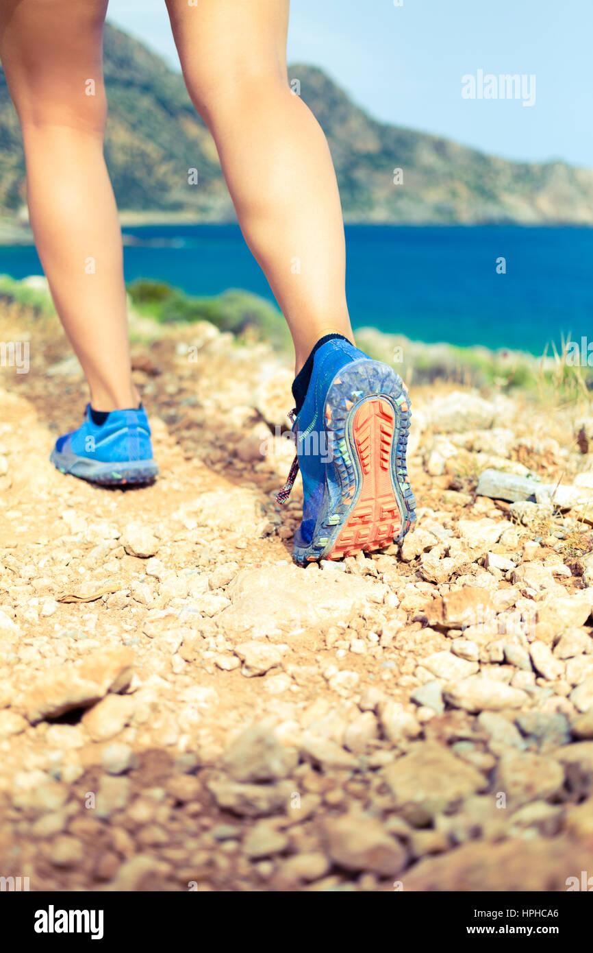 Hiking or running woman in beautiful mountains inspirational landscape. Sole of sports shoe and legs on rock trail. Hiker trekking or walking of footp Stock Photo
