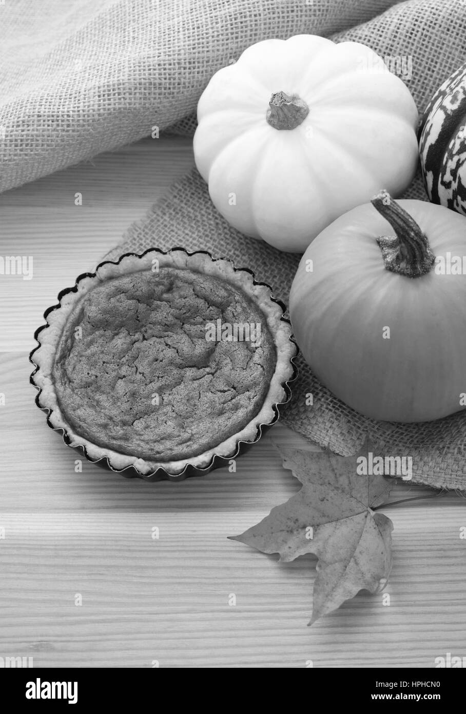 Mini pumpkin pie on a table with autumn gourds and maple leaf Stock Photo
