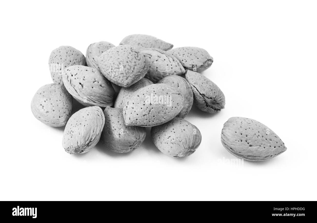 Small heap of whole almonds in shells, a single nut lies separate from the main pile, isolated on a white background Stock Photo