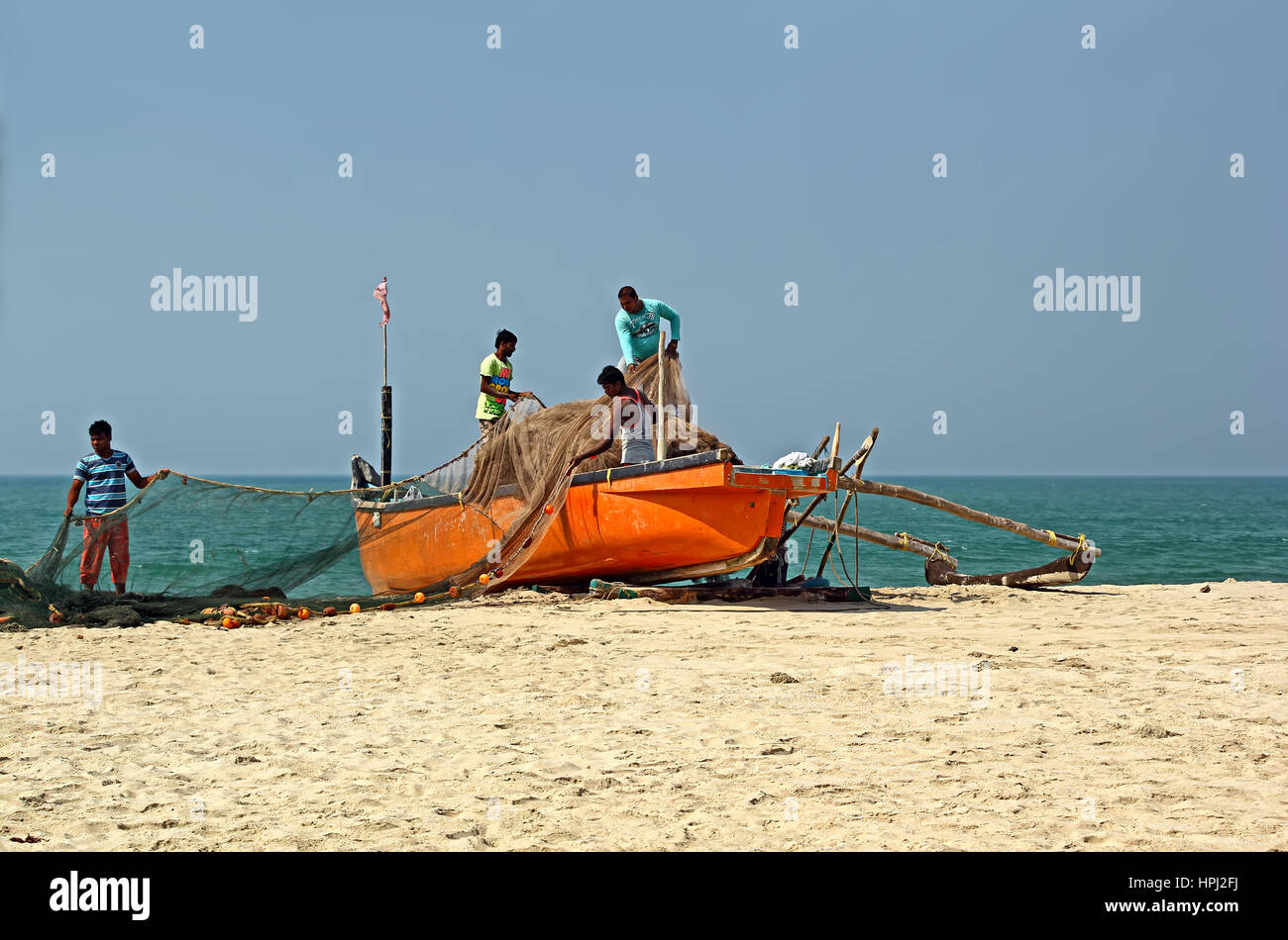 Velsao Beach, Goa, India. Unidentified fishermen systematically load the boat with large net in preparation of fishing trip to the deep sea Stock Photo