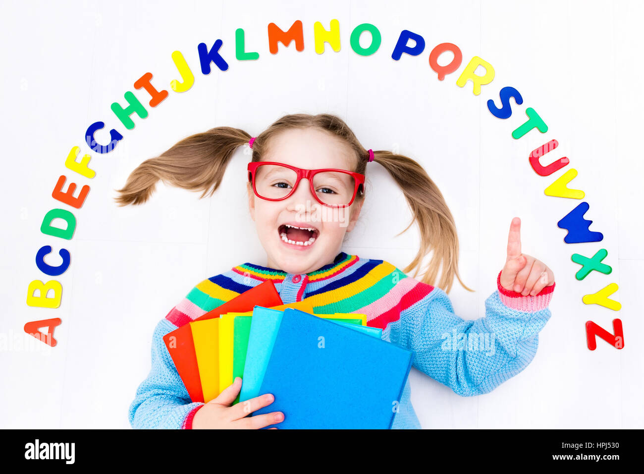 Happy preschool child learning to read and write playing with colorful