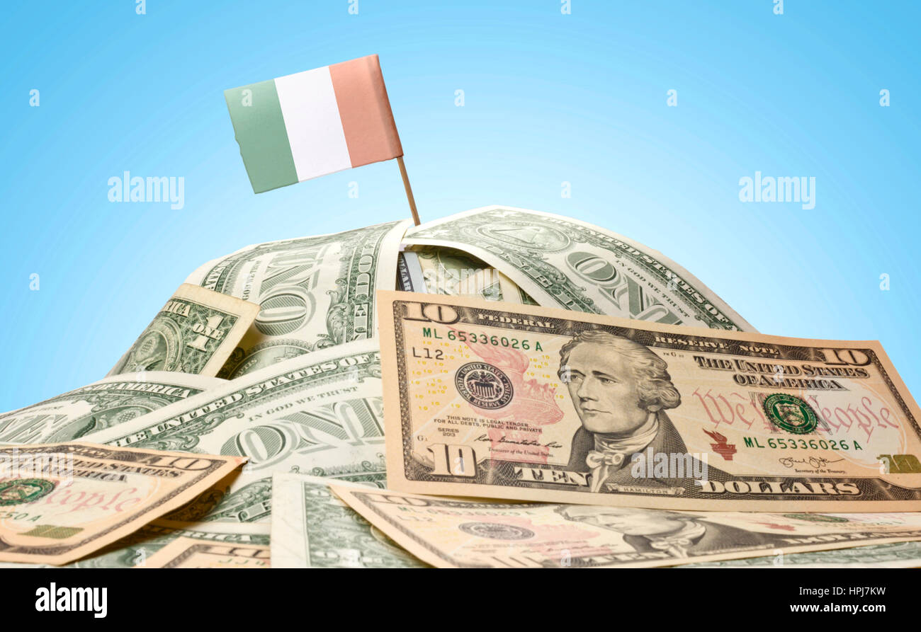The national flag of Ireland sticking in a pile of american dollars
