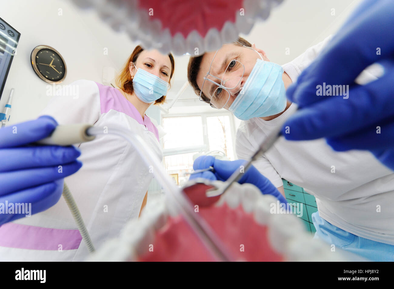 View from the mouth framed by teeth, focus on tools, inside view. Medical equipment.Dentist male and assistant girl visiting the oral cavity and the p Stock Photo
