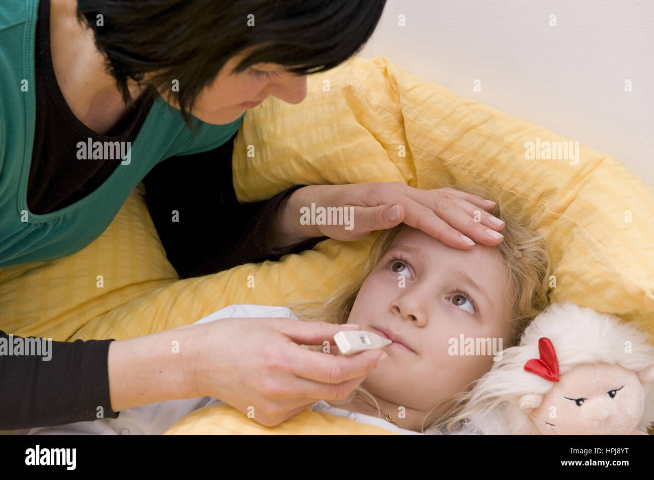 Model released , Krankes Maedchen im Bett, Mutter misst Fieber - sick girl n bed, mother with clinical thermometer Stock Photo