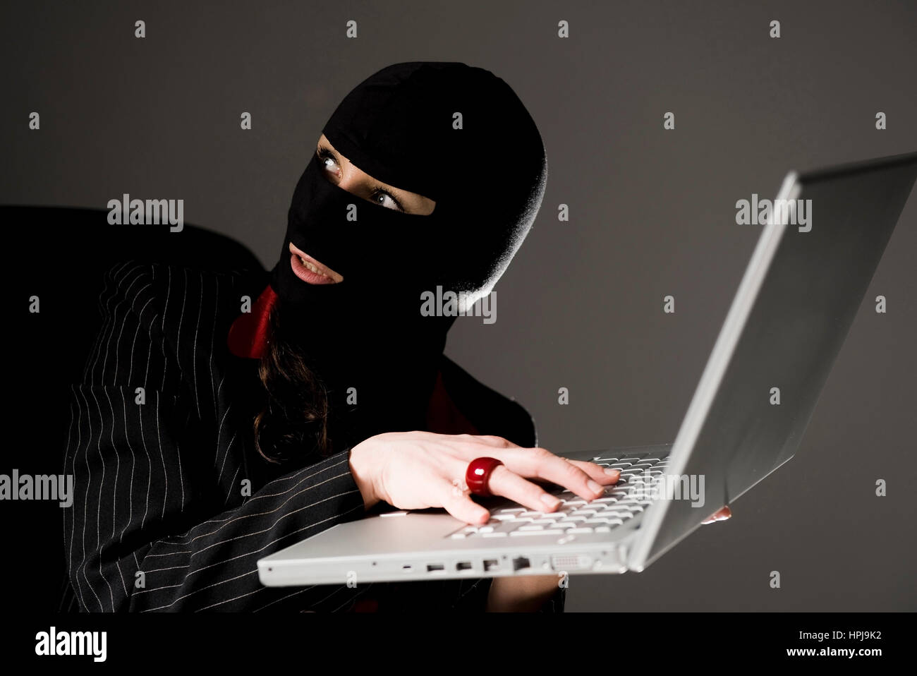 Model released , Maskierte Einbrecherin mit Laptop, Wirtschaftsspionage - symbolic for data piracy Stock Photo