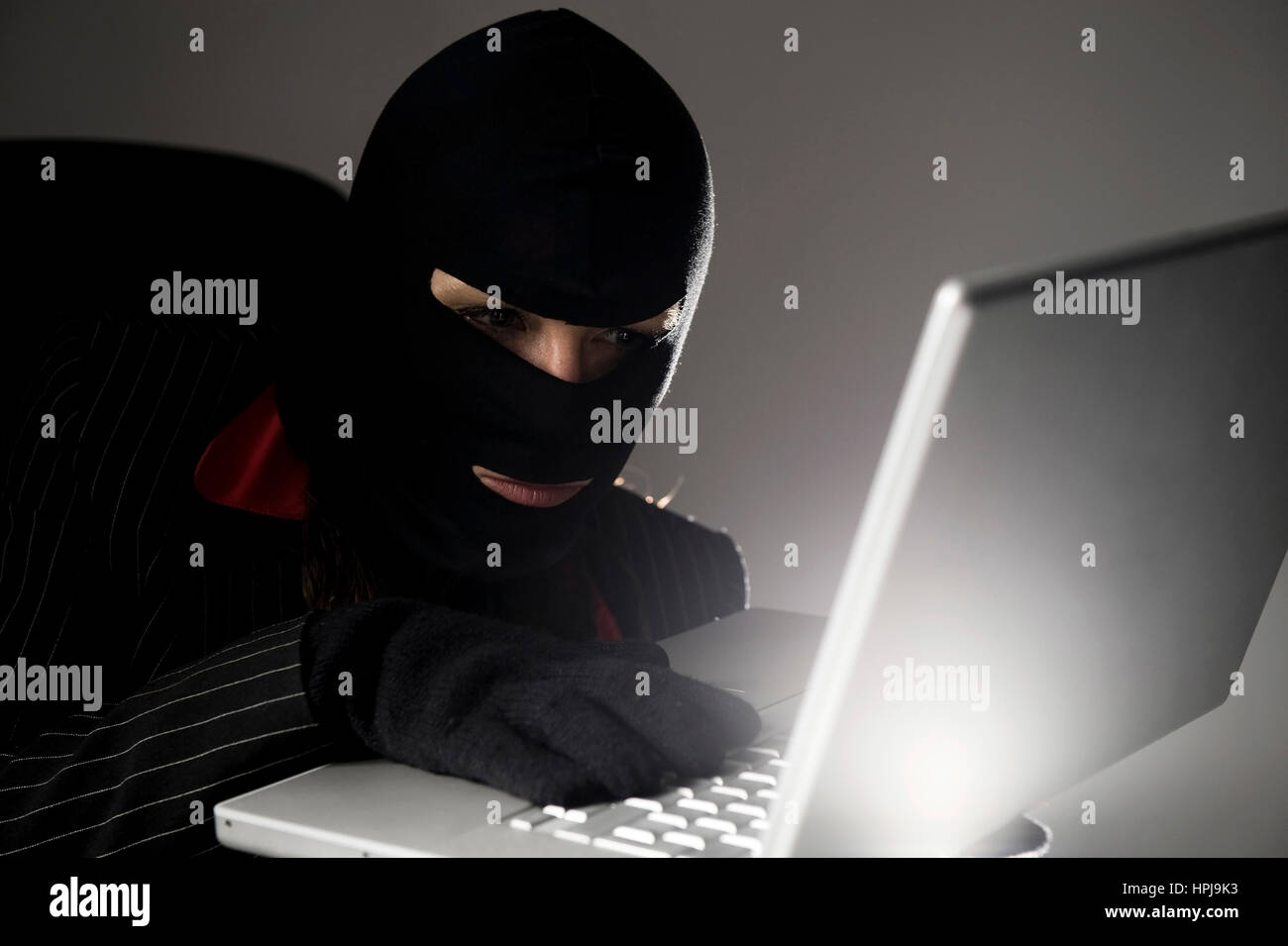 Model released , Maskierte Einbrecherin mit Laptop, Wirtschaftsspionage - symbolic for data piracy Stock Photo