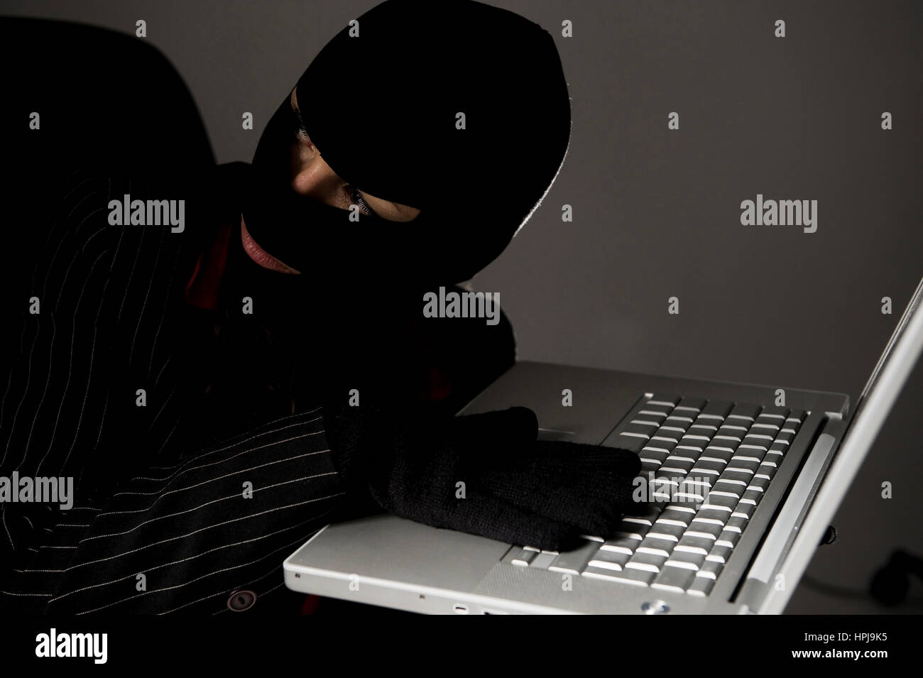 Model released , Maskierte Einbrecherin mit Laptop, Wirtschaftsspionage - symbolic for data piracy Stock Photo