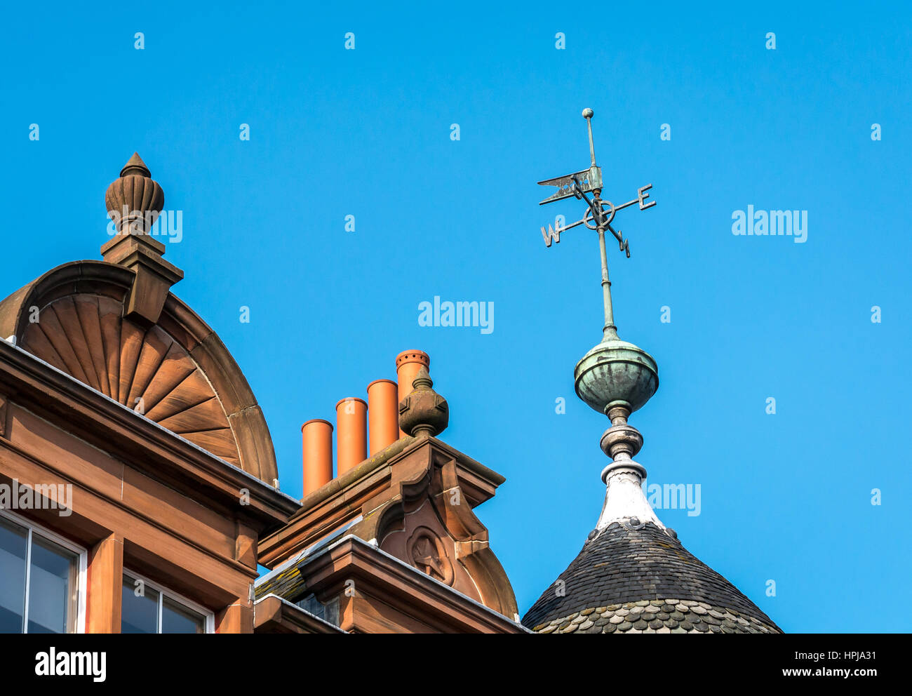 Close up view of weathervane on rooftop of old Victorian red sandstone building with chimney pots in Leith, Edinburgh, Scotland, UK Stock Photo