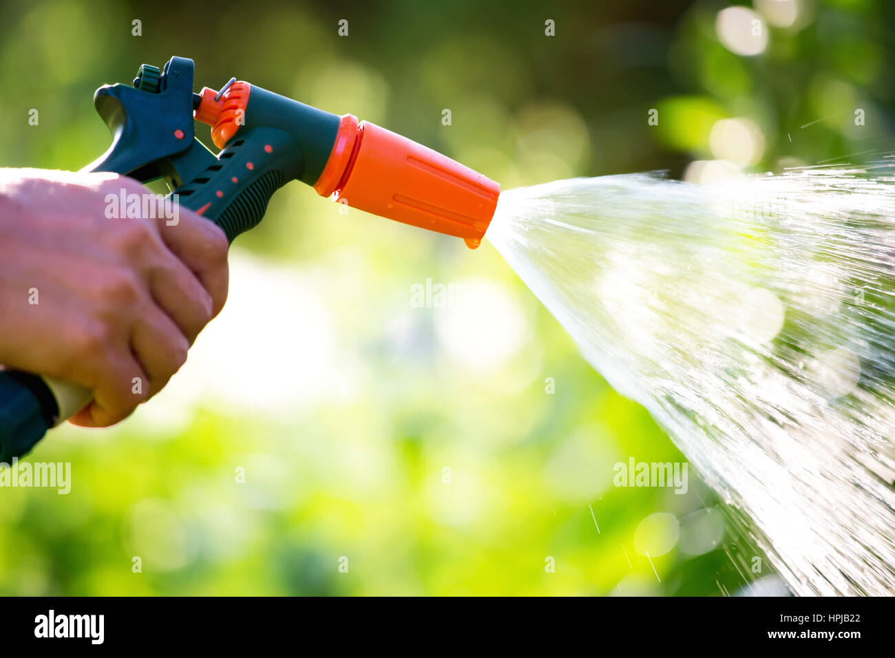 Hose garden sprinkler in woman hand. Watering garden with gun nozzle