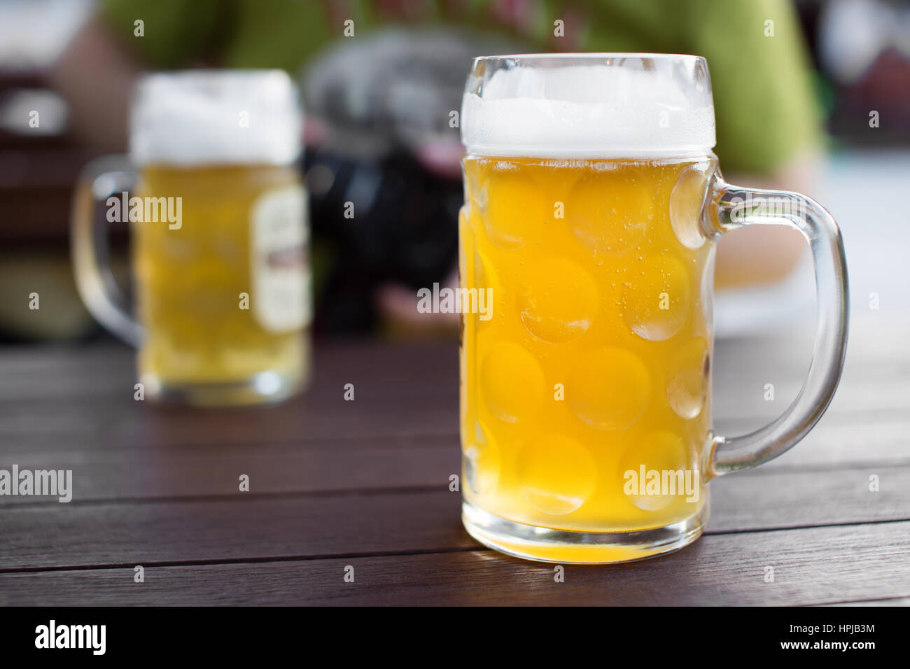 Glass of tapped craft beer. Pale ale on a pub table. Man drinking in