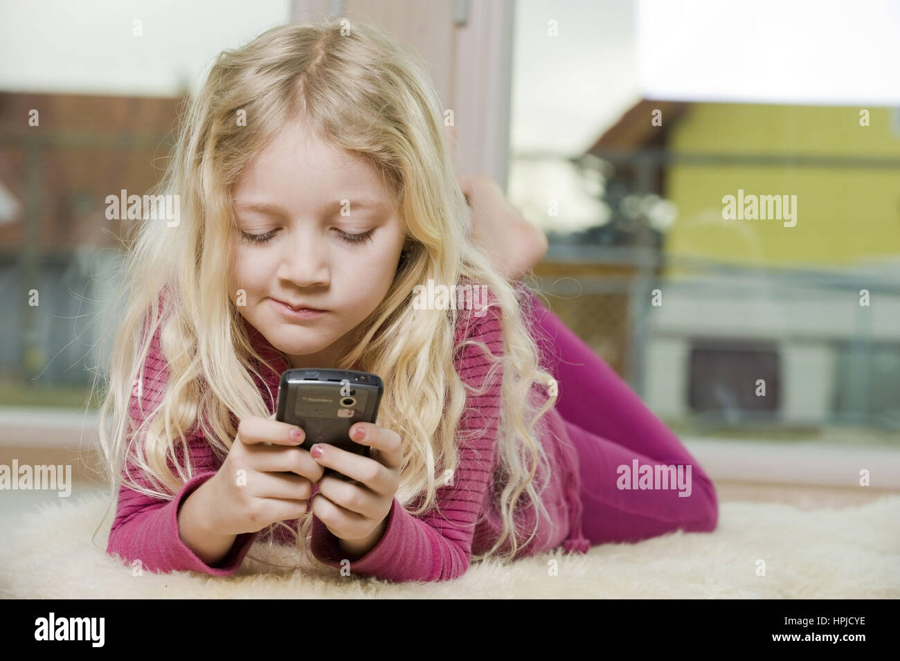 Model released , Maedchen liegt mit Handy am Fussboden - girl with mobile phone Stock Photo