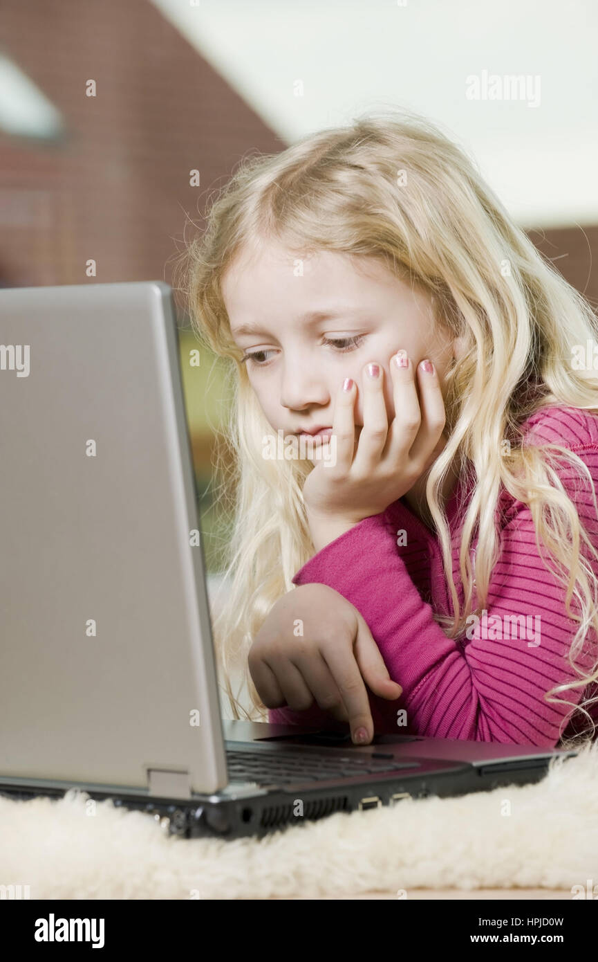 Model released , Maedchen, 8,  mit Laptop am Fussboden - girl using laptop Stock Photo