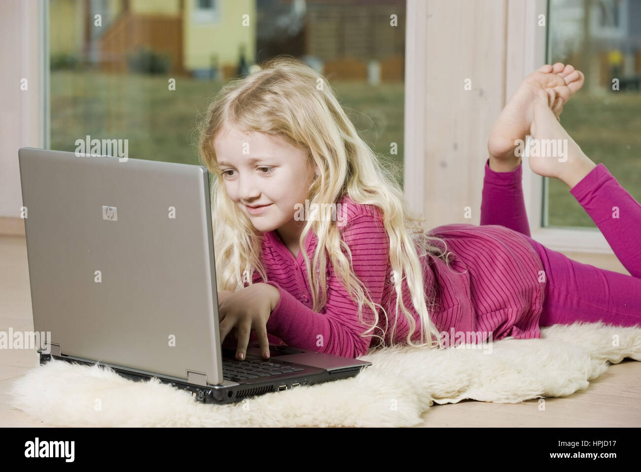 Model released , Maedchen, 8, mit Laptop am Fussboden - girl using laptop Stock Photo