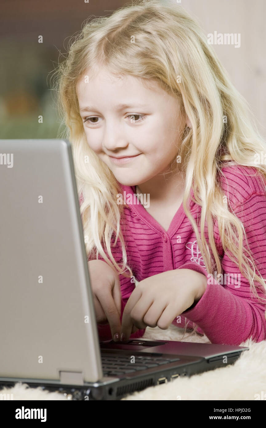 Model released , Maedchen, 8, mit Laptop am Fussboden - girl using laptop Stock Photo