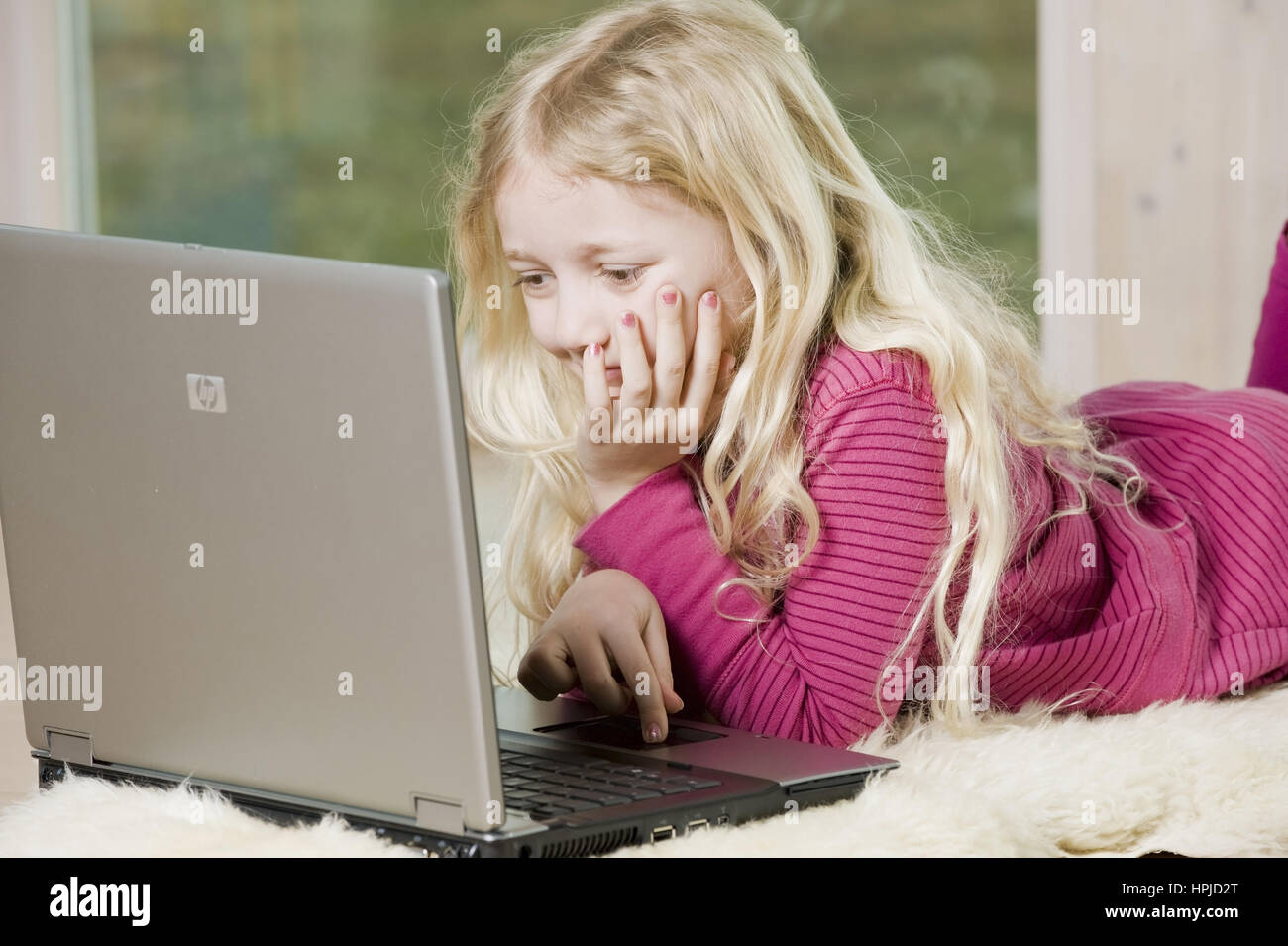 Model released , Maedchen, 8, mit Laptop am Fussboden - girl using laptop Stock Photo