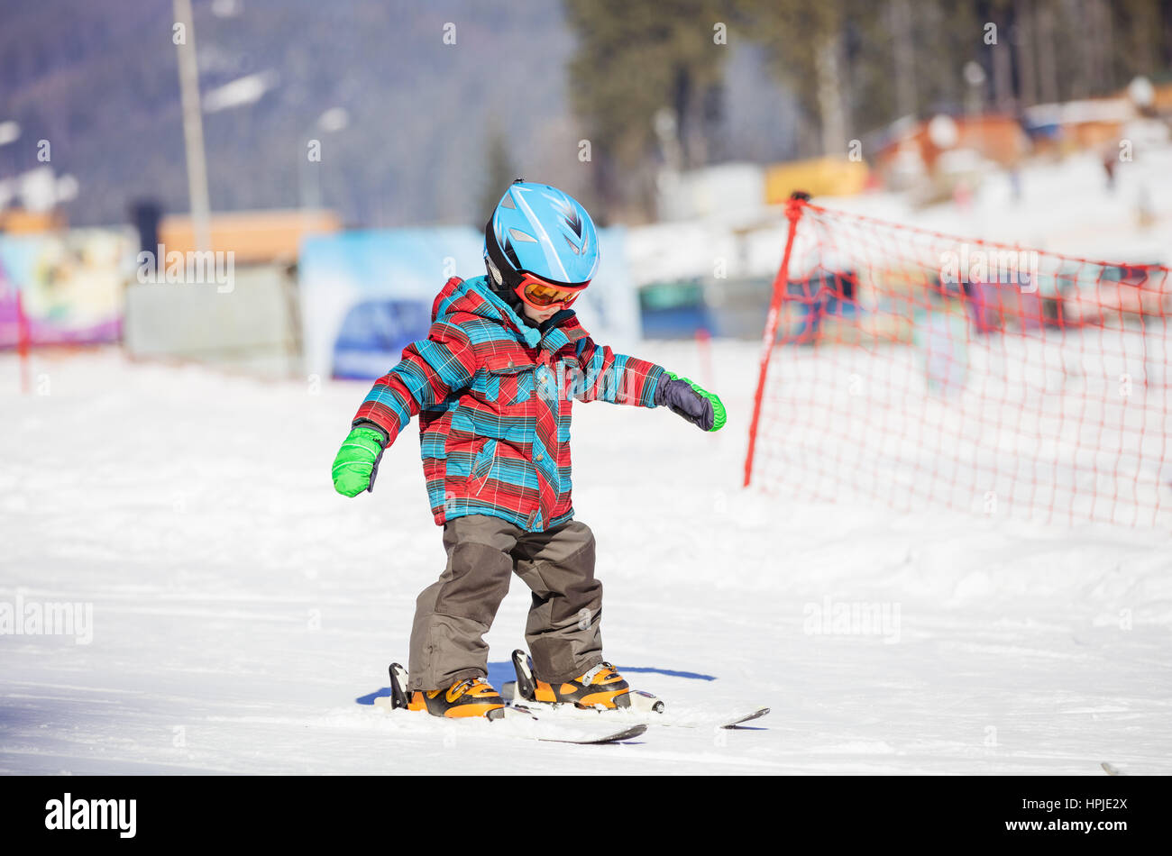 Little boy skiing downhill, wearing safety helmet and goggles Stock