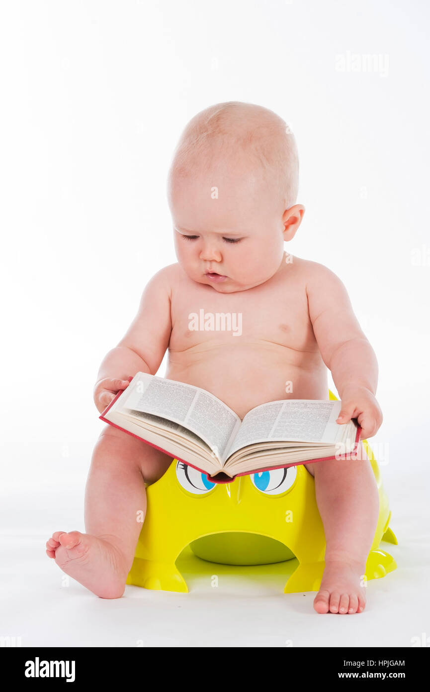 Model released , Baby, 10 Monate, sitzt mit Buch am Toepfchen - little child sitting on potty Stock Photo