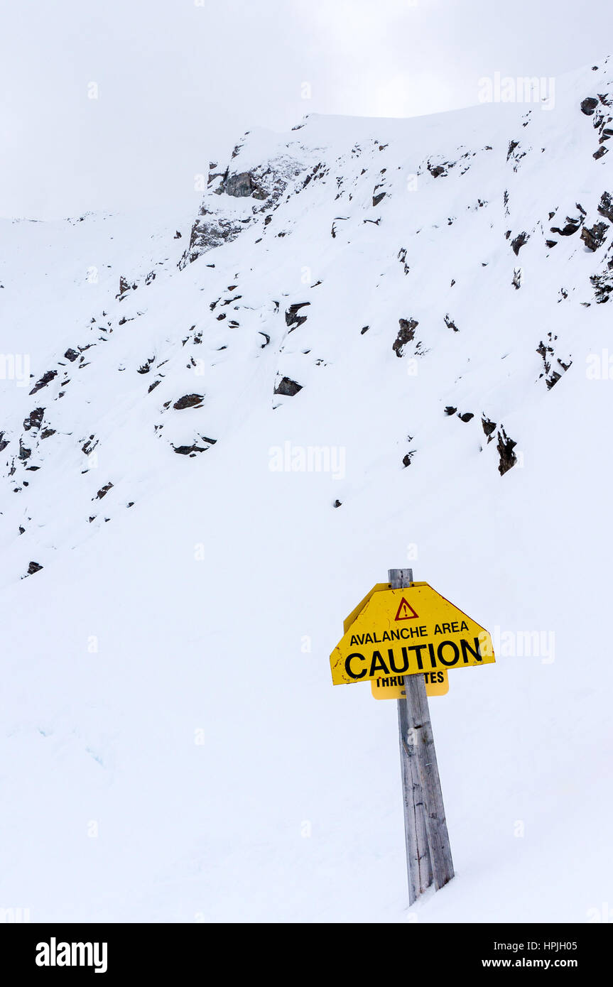 An avalanche area warning sign on top of Mount Whitehorn in Lake Louise, Alberta, Canada. Vertical orientation. Stock Photo