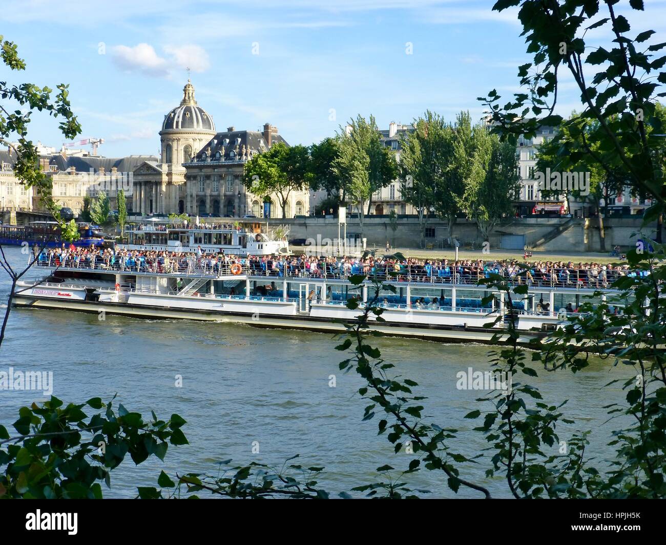 Tourists cruise up the River Seine in view from the Quai des Tuileries, Rive Droit. Paris, France. Stock Photo