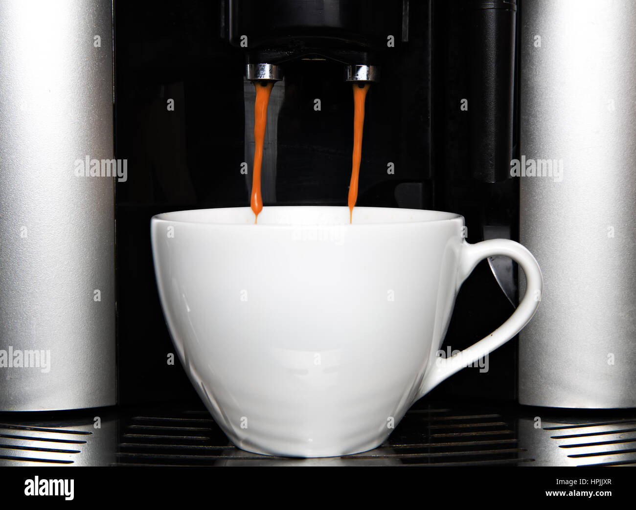 Espresso pouring from coffee machine into a white cup Stock Photo