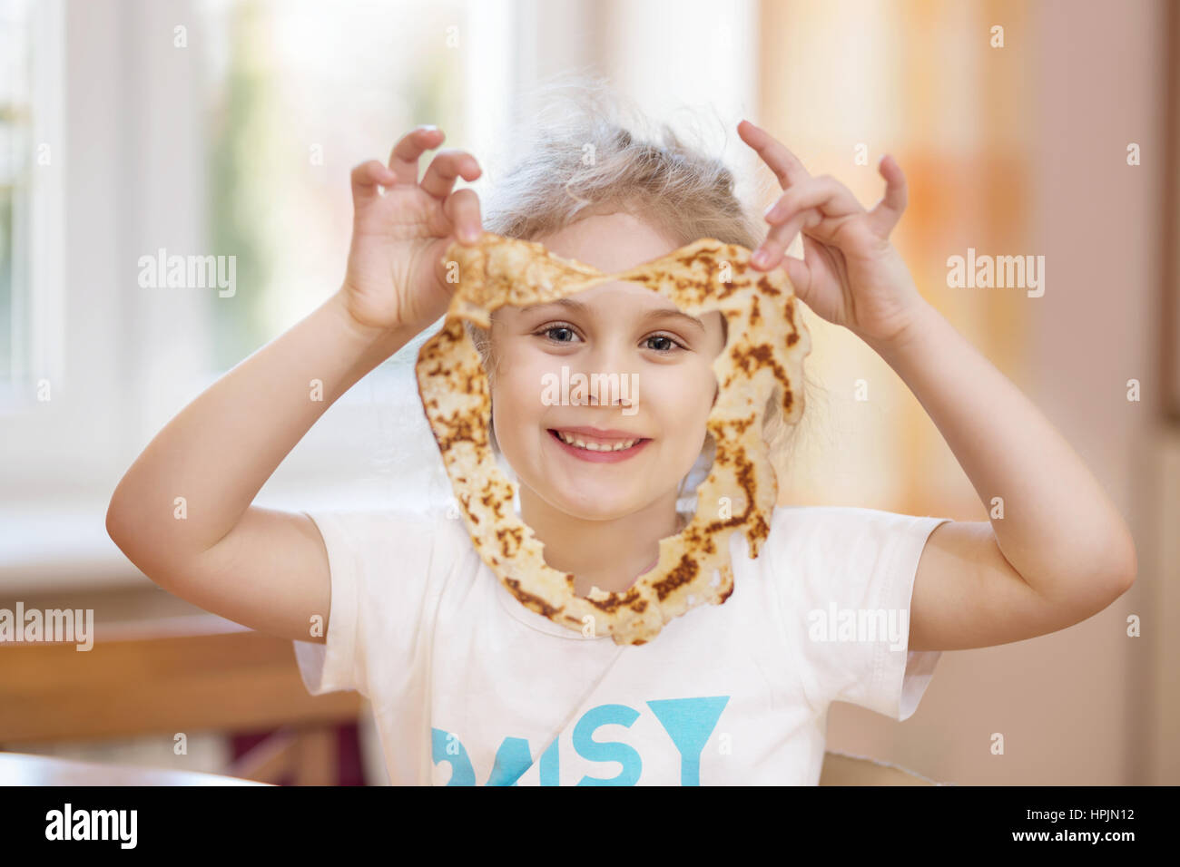 Cheerful girl with pancake in the kitchen at home Stock Photo