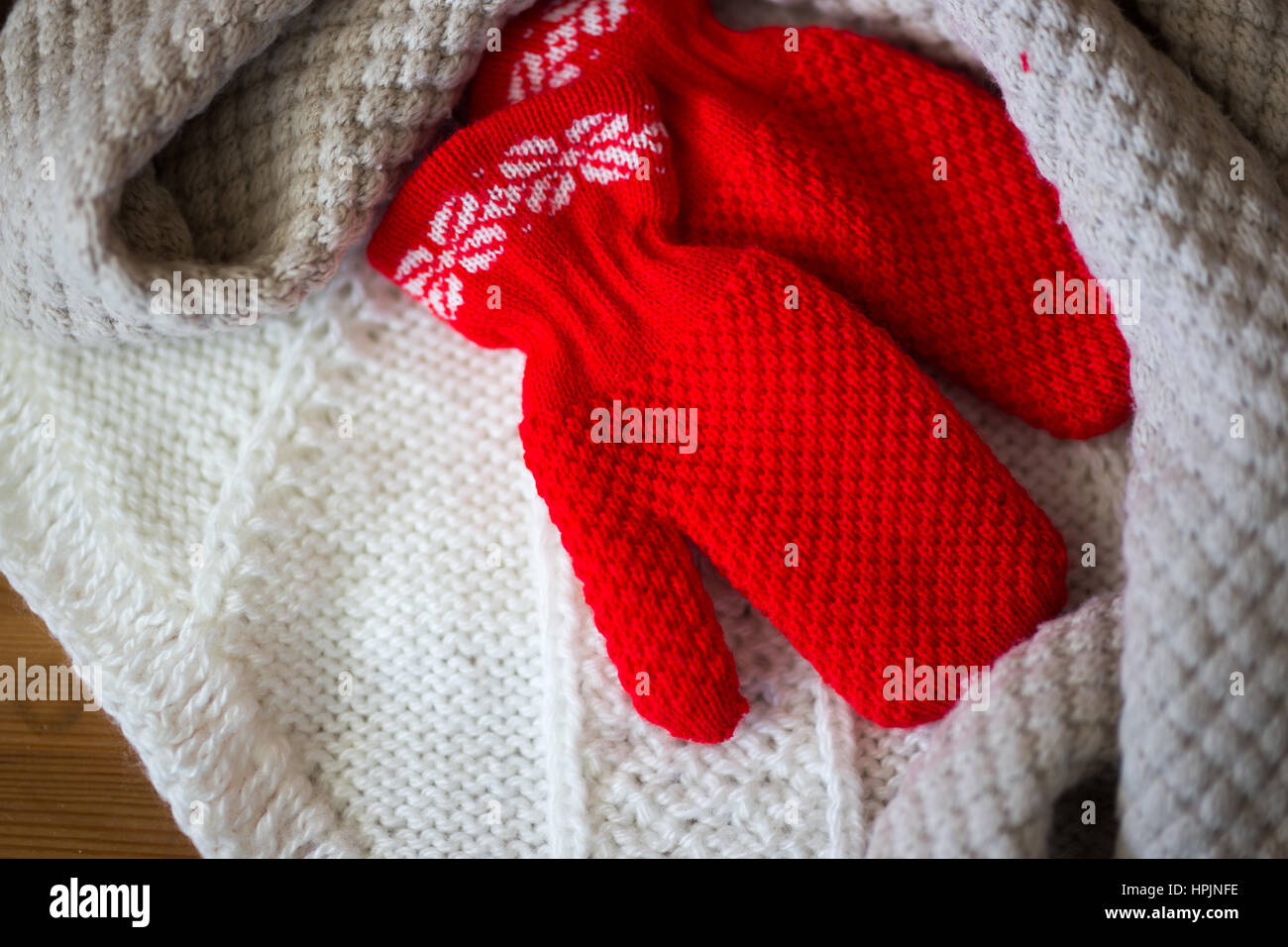 Winter baby clothes, scarf and mittens on wooden background Stock Photo