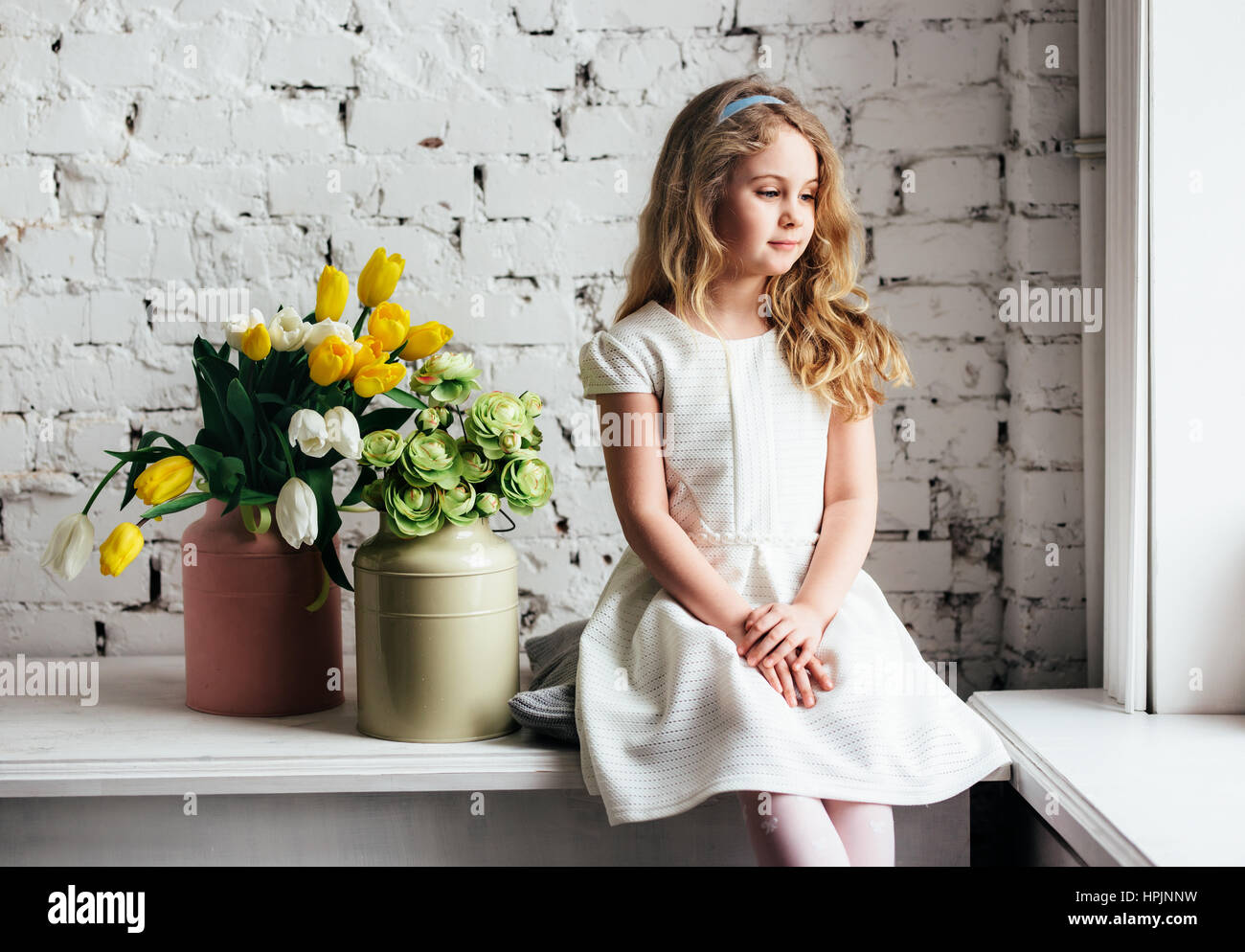 Little blonde girl in a white dress sitting by the window Stock Photo ...