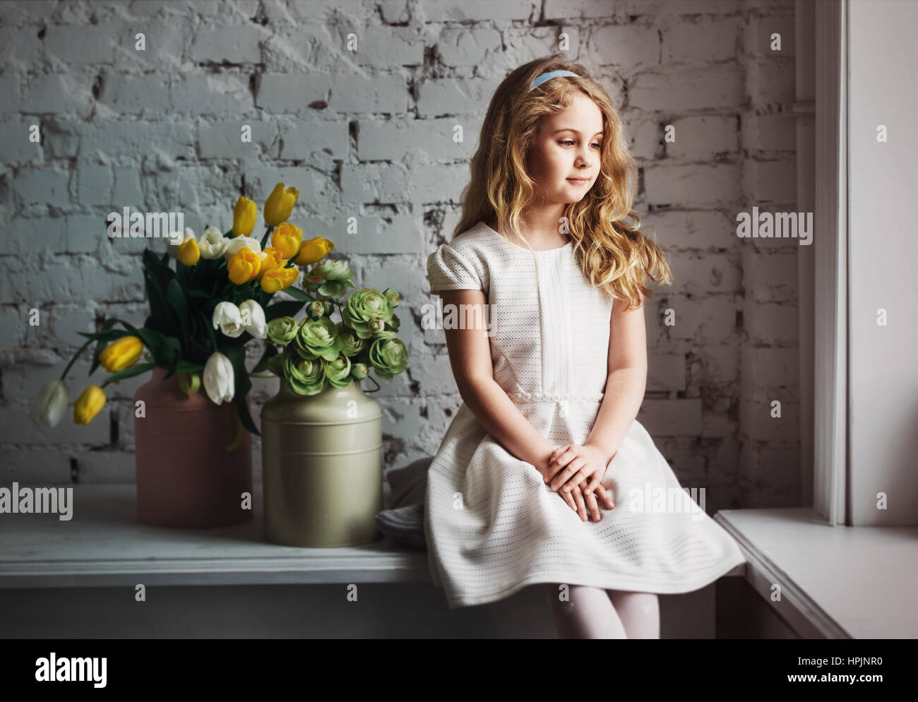 Little blonde girl in a white dress sitting by the window Stock Photo ...
