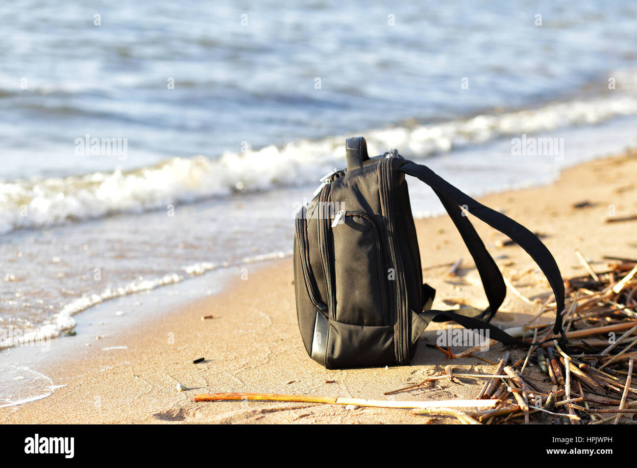 Black backpack on the sand on the seaside Stock Photo
