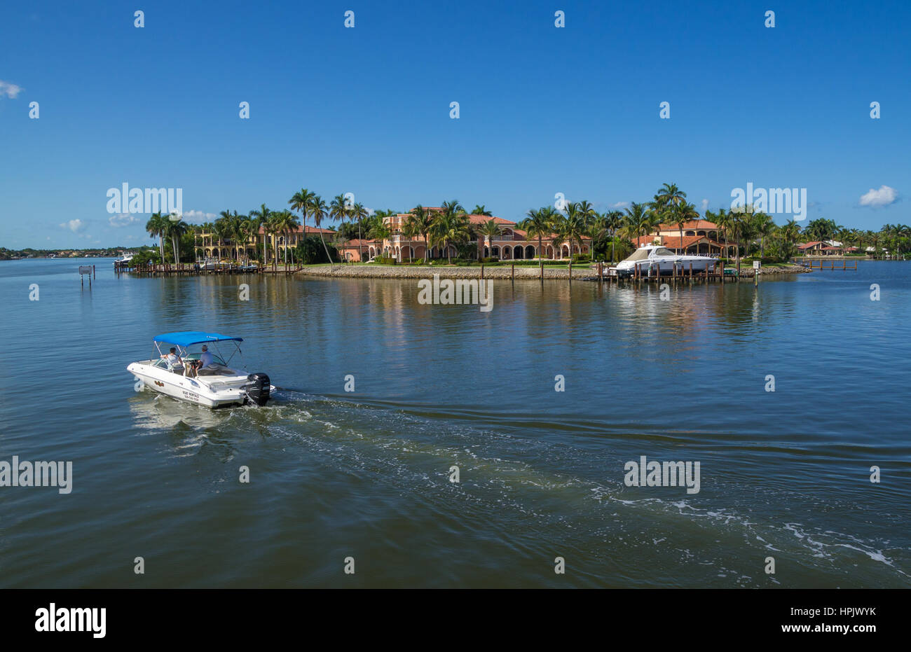 NAPLES, FLORIDA USA May 8 2013 Rental Boat Cruising Past Large Luxury Waterfront Mansion in