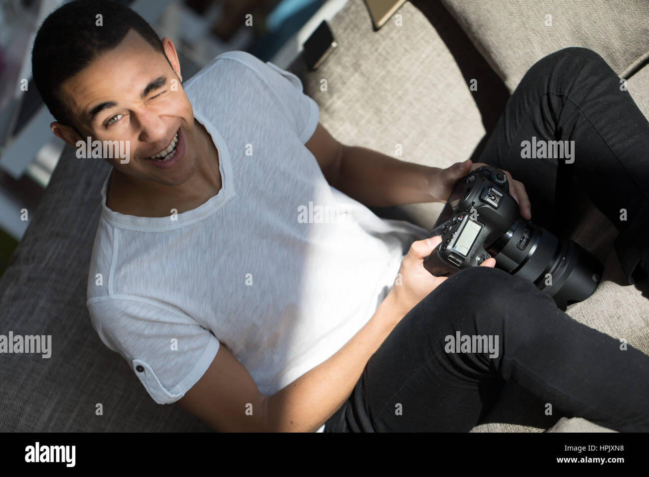 funny face of a man with a ray of light in his face while checking his photographs on his digital single lens reflex photocamera Stock Photo