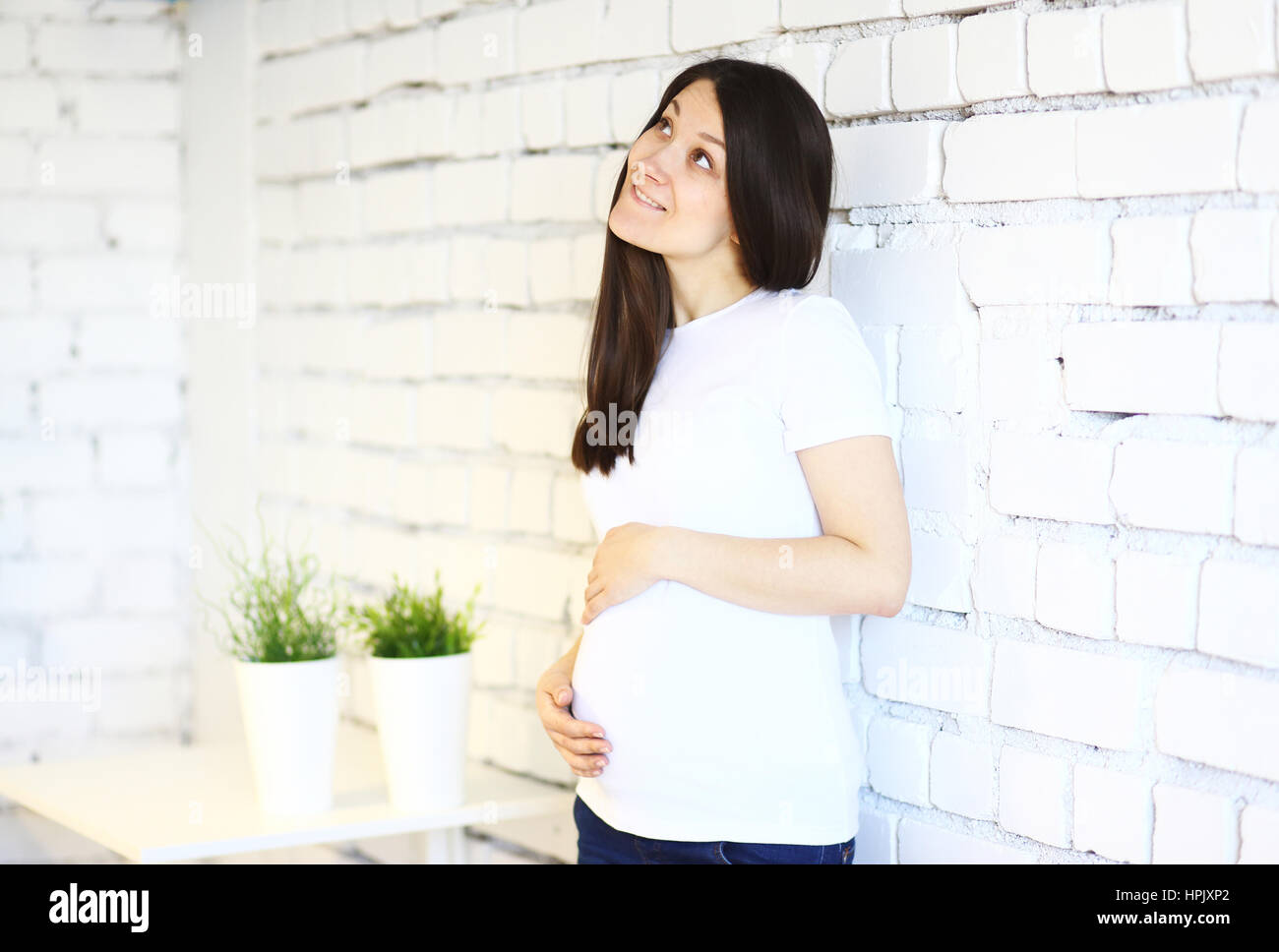Young pregnant woman thinking about her child on white break background Stock Photo