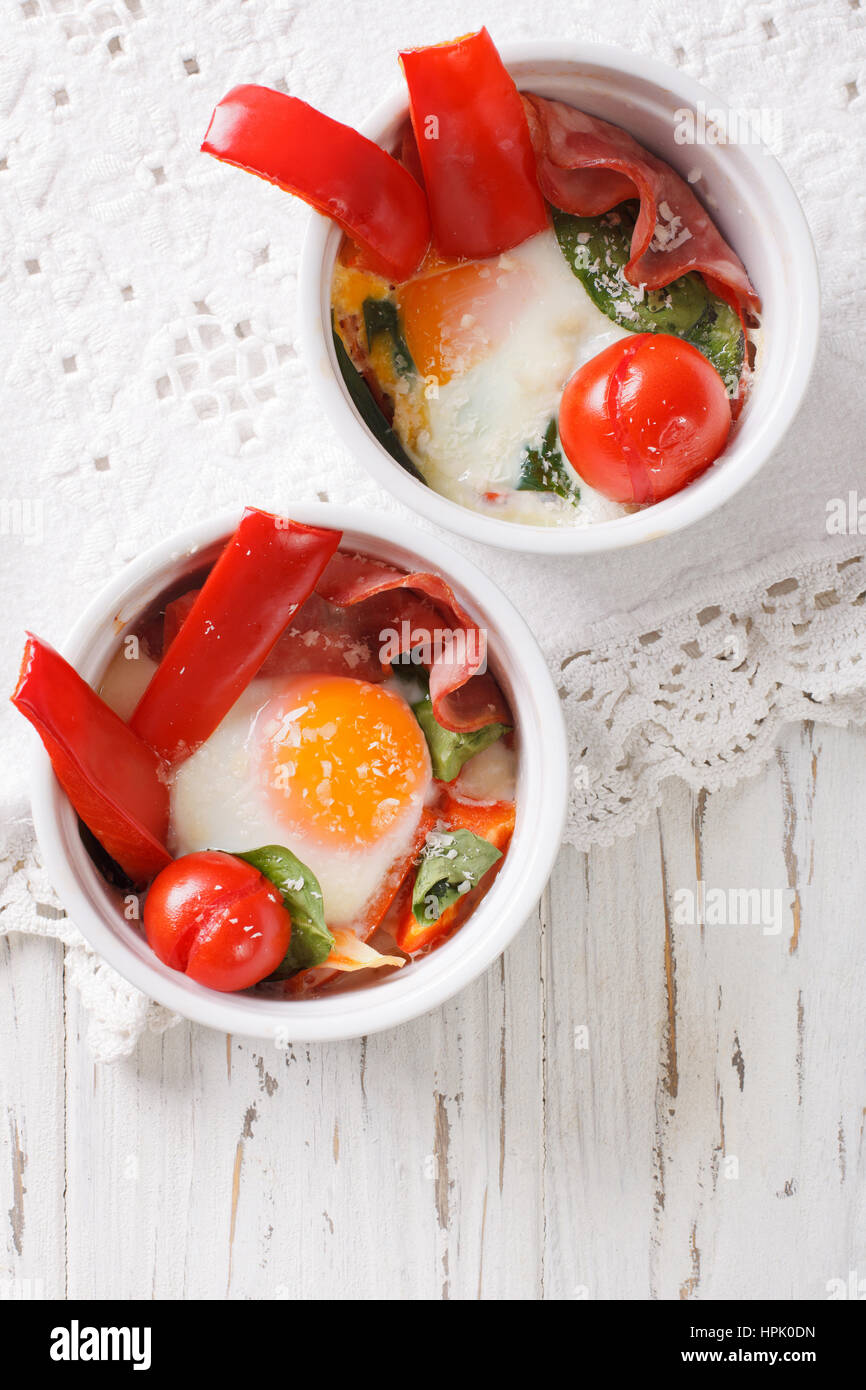 Baked egg with spinach, peppers, tomatoes and cheese in a cup closeup