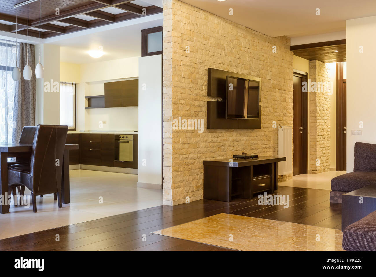 Modern living room and modern kitchen. The wall with natural stone bricks and tv on it. Stock Photo