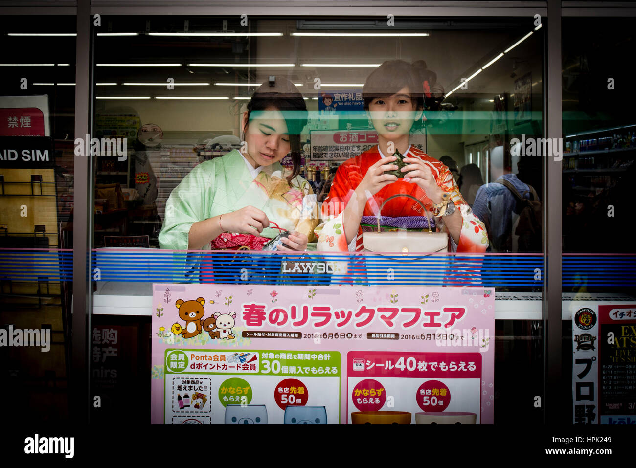 Two young women in kimono eating snacks in a convenient store, Kyoto, Japan Stock Photo
