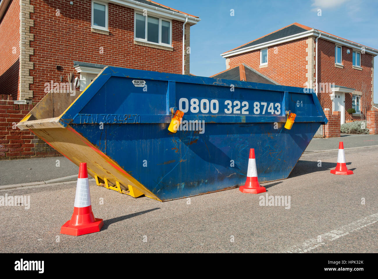 Rubbish skip (dumpster) on a residential road with cones and light around it Stock Photo Alamy